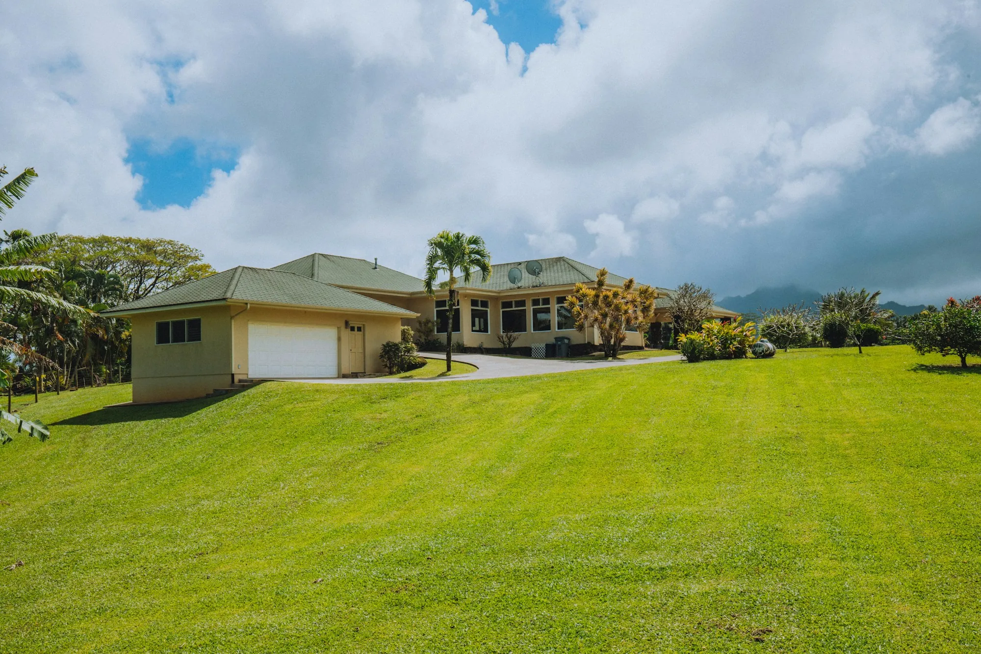 Single-story homes with a broad lawn and hills in the distance