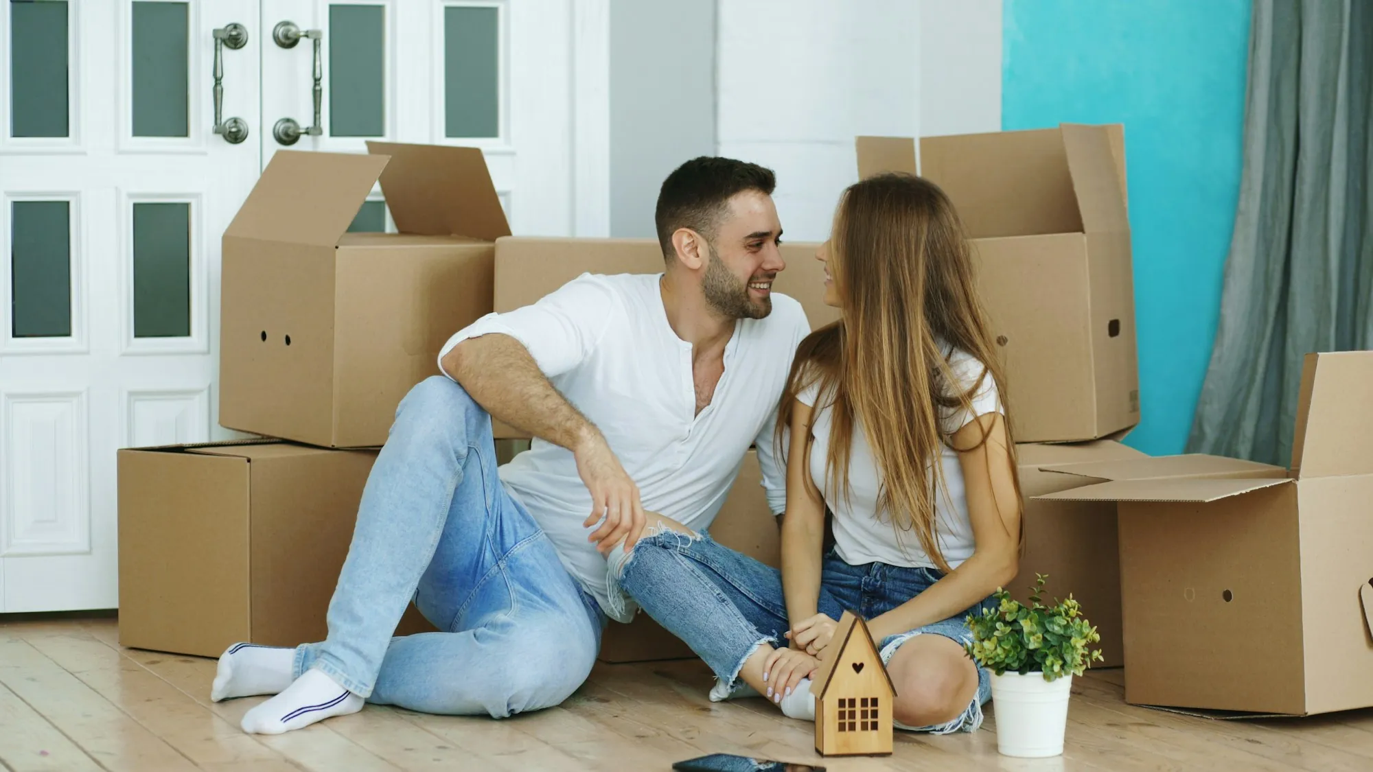 Couple sitting between moving boxes in a new home, thinking through Prop 19 property tax after a move in Porterville